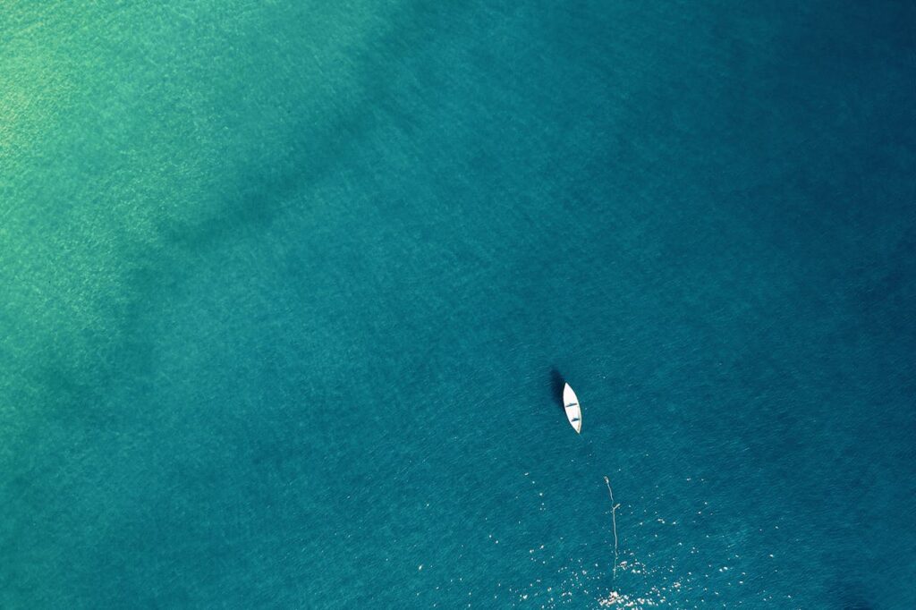 Aerial view of a lone boat on calm turquoise waters, showcasing tranquility.